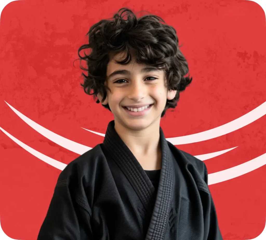 A Male Middle Eastern Child is Wearing a black Gi against a red background | youth jiu jitsu near me | Sixth Sense Martial Arts | Coppell, TX