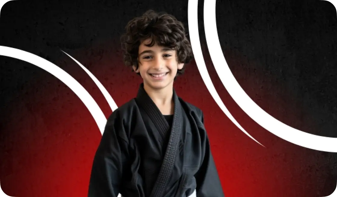 A young Male Middle Eastern Child is Wearing a black Gi against a red background | jiu jitsu near me prices | Sixth Sense Martial Arts | Coppell, TX